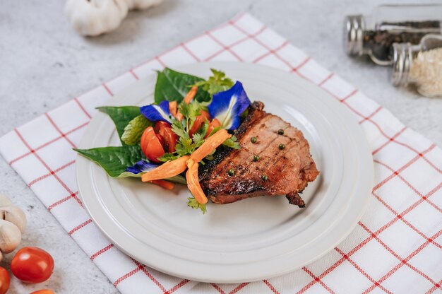 Bistecca di maiale con pomodoro, carota, cipolla rossa, menta piperita, fiore di pisello farfalla e lime.