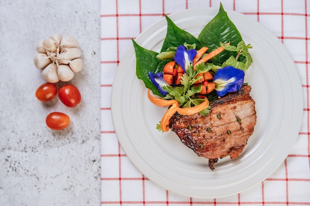 Bistecca di maiale con pomodoro, carota, cipolla rossa, menta piperita, fiore di pisello farfalla e lime.