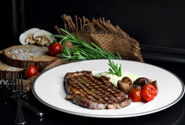 Bistecca di manzo servita con riso, funghi e pomodoro