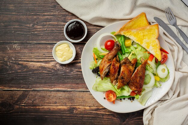 Bistecca di pollo alla griglia e verdure su fondo di legno scuro