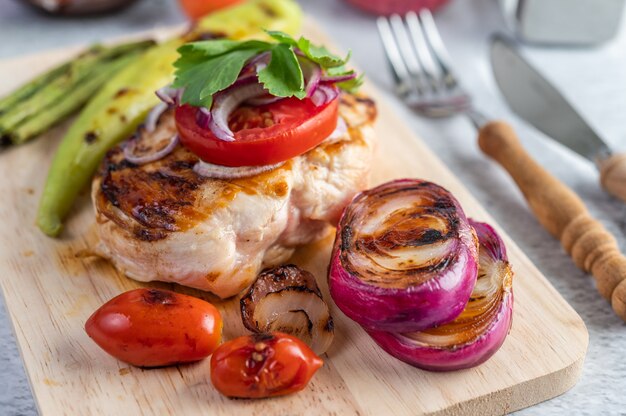 Bistecca di pollo disposta su un vassoio di legno.