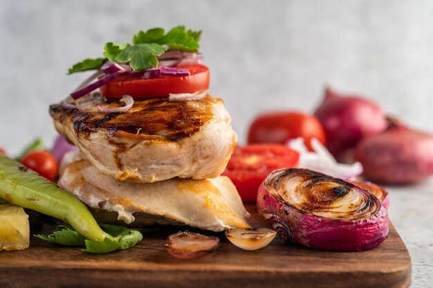 Bistecca di pollo disposta su un vassoio di legno.