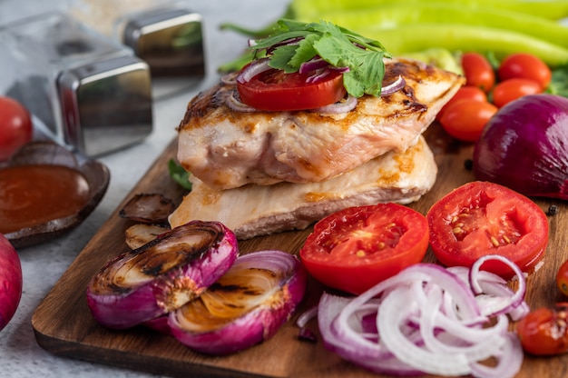 Bistecca di pollo disposta su un vassoio di legno.