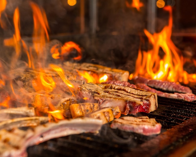 Bistecche di carne troppo cotte in fiamme sulla griglia