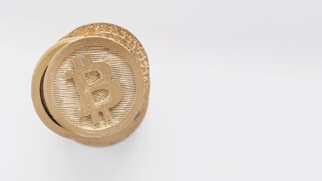 Bitcoins dorati impilati su fondo bianco