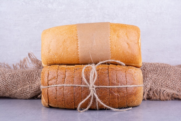 Blocchi di pane interi e affettati sulla superficie di marmo