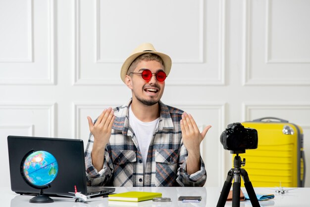 Blogger di viaggio in cappello di paglia giovane bel ragazzo che registra un vlog di viaggio sulla fotocamera che invita a unirsi a lui