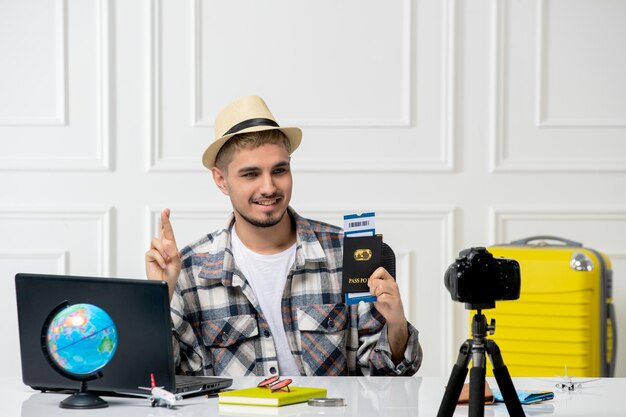 Blogger di viaggio in cappello di paglia giovane bel ragazzo che registra un vlog di viaggio sulla fotocamera che sogna un viaggio