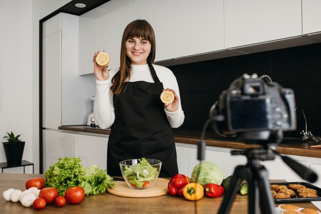 Blogger femminile di smiley che si registra mentre prepara l'insalata