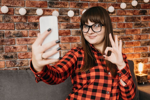 Blogger femminile in streaming online con smartphone e dando segno ok