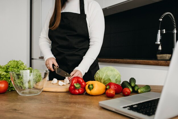 Blogger femminile streaming di cucina con il computer portatile a casa