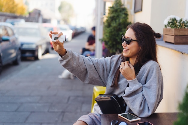 Blogger femminile sveglio e giovane che posa sulla macchina fotografica.