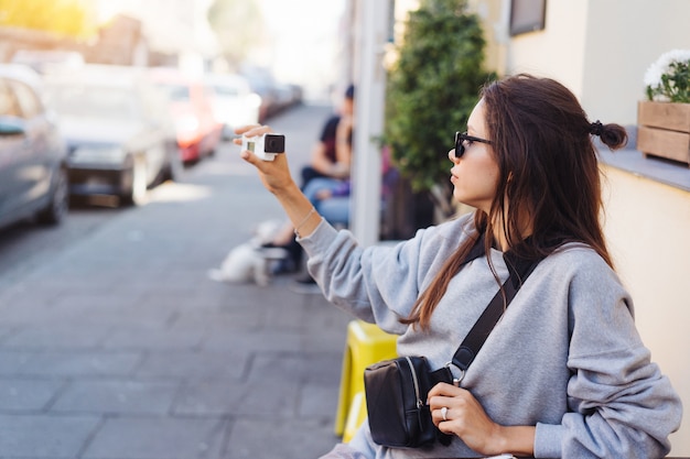 Blogger femminile sveglio e giovane che posa sulla macchina fotografica.