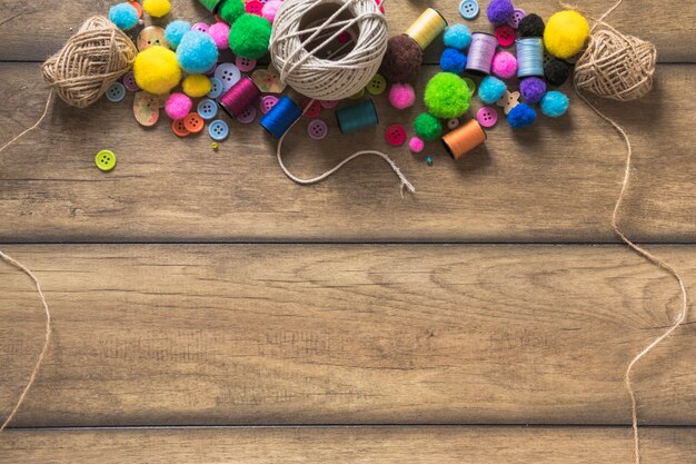 Bobina di stringa; bottoni colorati; rocchetto e batuffoli di cotone su tavola di legno