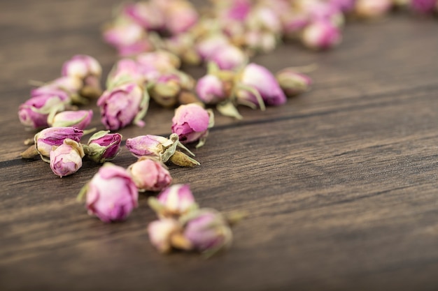 Boccioli di fiori rosa essiccati posti su un tavolo di legno