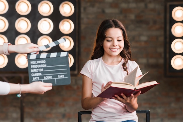 Bordo di valvola femminile della holding davanti al libro di lettura della ragazza