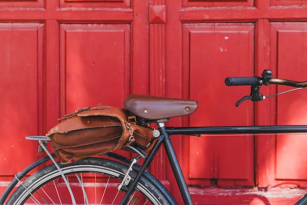 Borsa marrone in bicicletta contro la porta rossa chiusa