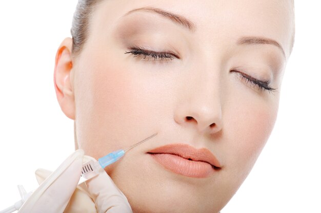 Botox sparato nella guancia femminile - primo piano del fronte femminile