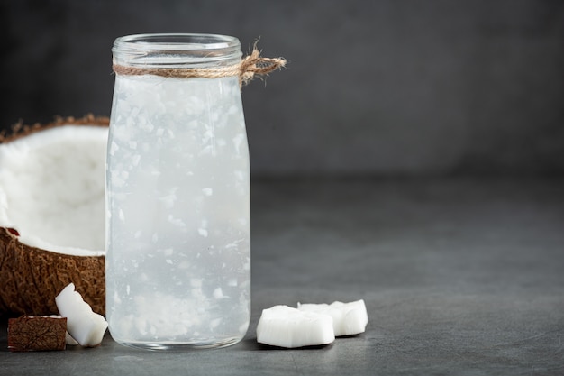 bottiglia di acqua di cocco messa su sfondo scuro