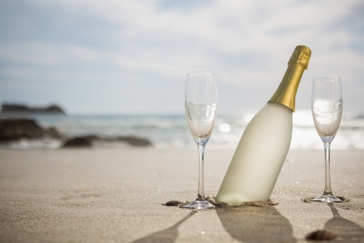Bottiglia di champagne e due bicchieri sulla sabbia