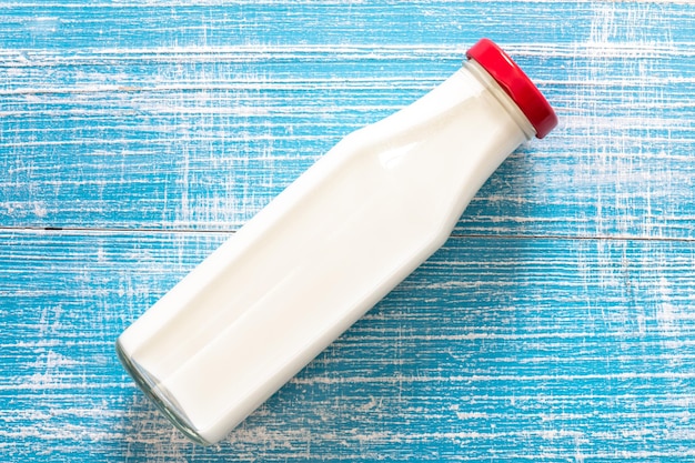 Bottiglia di latte su uno sfondo blu di legno piatto
