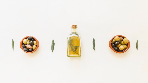 Bottiglia di olio con ciotole con olive