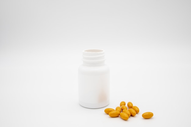 Bottiglia di pillola bianca e pillole arancioni contro una priorità bassa bianca