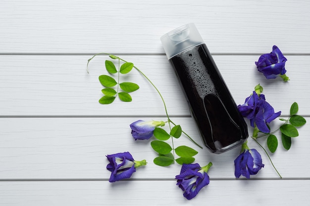 Bottiglia di shampoo di Butterfly Pea Flower messa su fondo di legno bianco