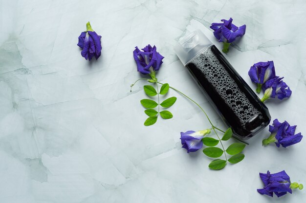 Bottiglia di shampoo di Butterfly Pea Flower messa su sfondo bianco marmo