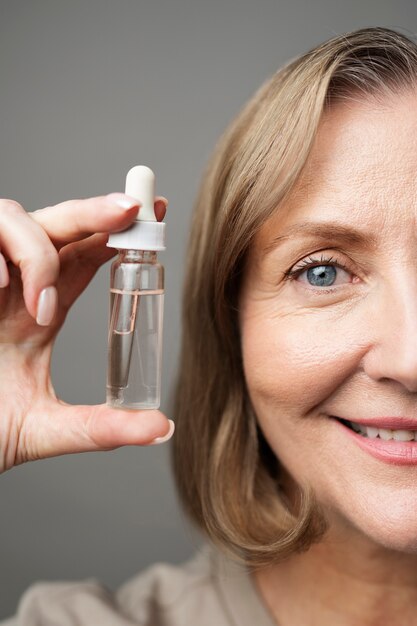 Bottiglia di siero della holding della donna maggiore