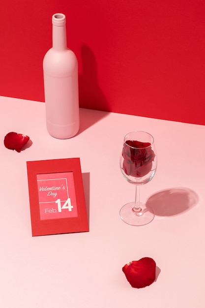 Bottiglia di vino ad alto angolo di mani con rosa in vetro e biglietto di San Valentino