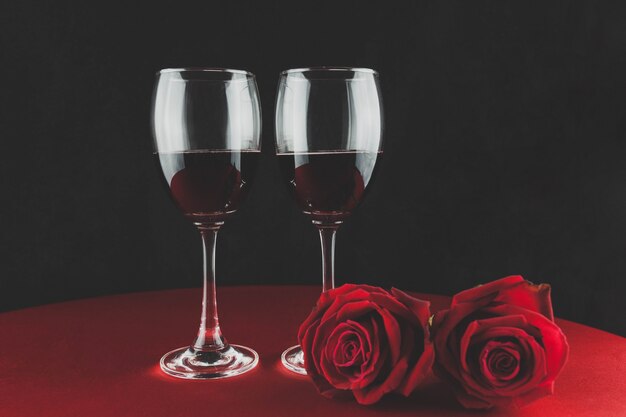 Bottiglia di vino con dos copas y una rosa encima de una mesa