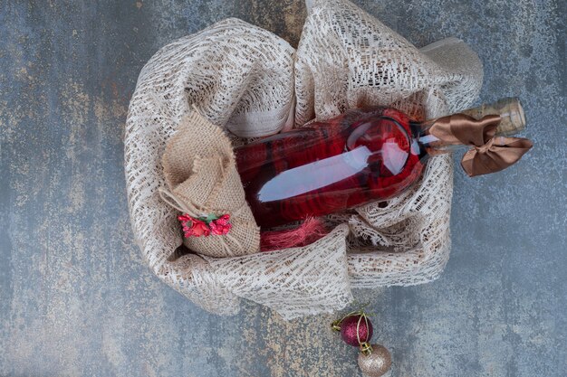 Bottiglia di vino decorata con nastro in cestino di legno. Foto di alta qualità