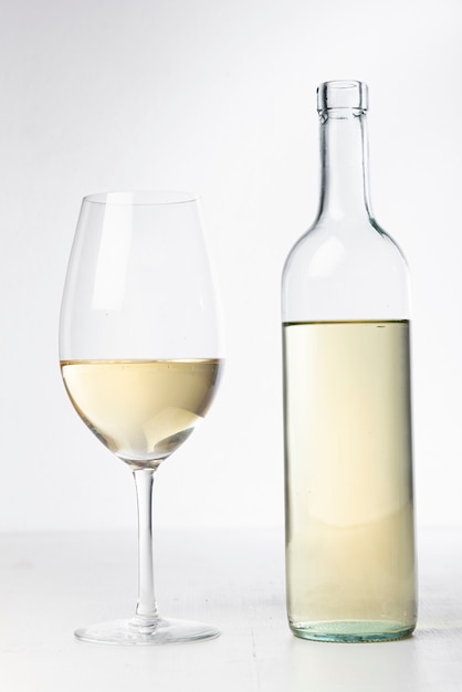 Bottiglia e bicchiere di vino trasparenti del primo piano