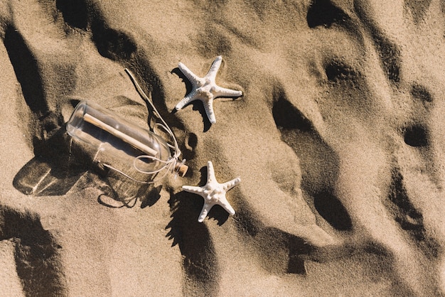 Bottiglia e starfishes sulla sabbia