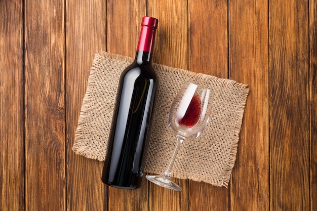 Bottiglia piena di vino rosso e bicchiere vuoto