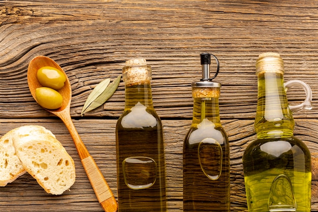 Bottiglie di olio piatto laici e cucchiaio di legno