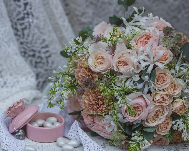Bouquet da sposa color pastello, abito da sposa e barattolo di caramelle