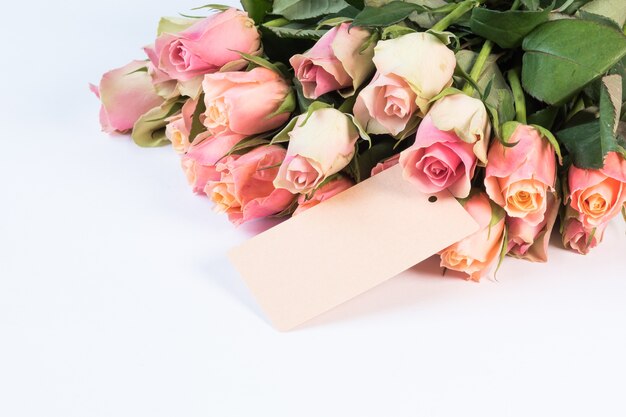 Bouquet di bellissime rose rosa con una carta isolata su uno sfondo bianco
