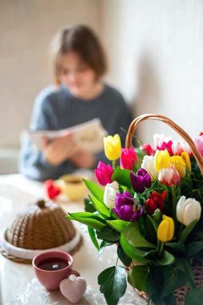 Bouquet di fiori con una ragazza che scrive sul tavolo. Cucina