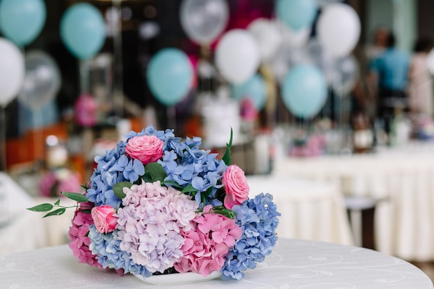 Bouquet di ortensie e rose rosa e blu si trova sulla tavola bianca