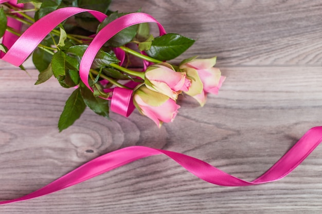 Bouquet di rose con nastro rosa su legno