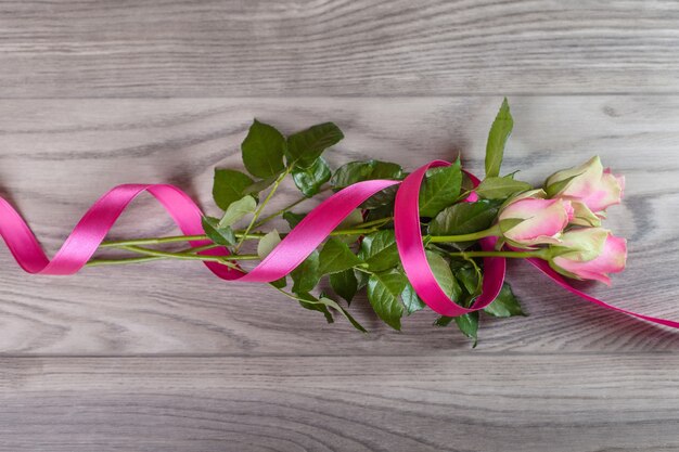 Bouquet di rose rosa avvolte in nastro su legno