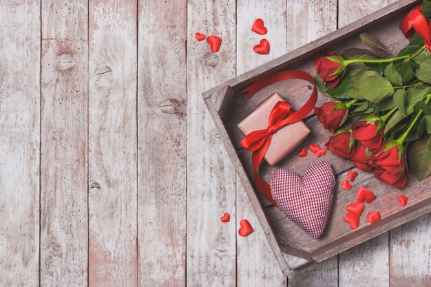 Bouquet di rose su un vassoio con un cuore e un dono