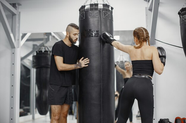 Boxe donna. Principiante in palestra. Signora in abbigliamento sportivo nero. Donna con allenatore.