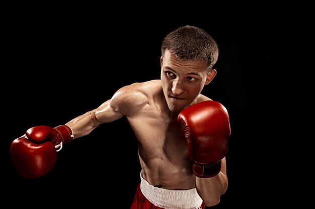 Boxer maschio boxe con drammatica illuminazione tagliente in uno studio buio