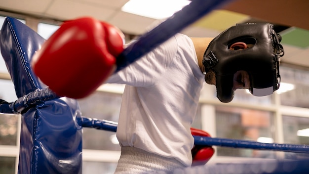 Boxer maschio con casco e guanti sul ring praticando