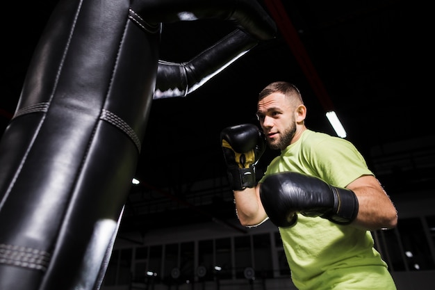 Boxer maschio in guanti protettivi con sacco da boxe