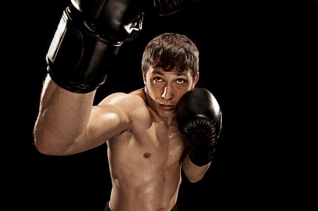 Boxer maschio nel sacco da boxe con drammatica illuminazione tagliente
