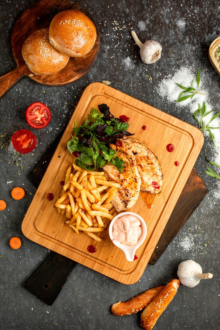 Foto gratuito braciola e patate fritte di pollo su un bordo di legno